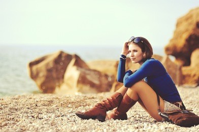 glamourous portrait of the young beautiful woman  in leather boots on the bank of a beach