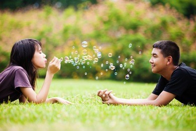 teenager asian girl blowing soap bubbles for brother