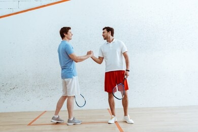two squash players with rackets shaking hands and looking at each other
