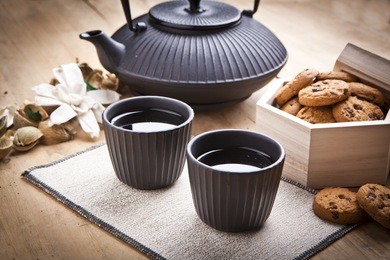 beautiful teapot with chocolate biscuits on wooden table, delicious breakfast