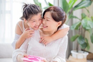 happy mother day - daughter give card and gift to her mom at home