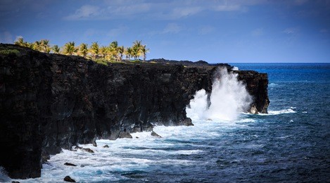 waves crash along the black lava rock cliffs in the hawaiian volcanoes national park.   this view is at the end of the chain of craters road