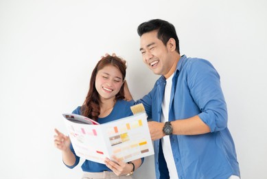happy asian couple choosing colour palette for their new house, lifestyle concept.