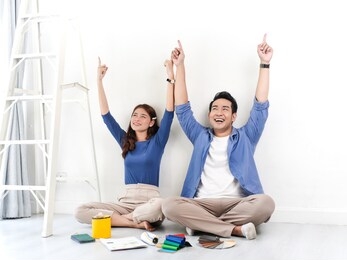asian couple sitting on floor and pointing up with colour palette for their new house, lifestyle concept.
