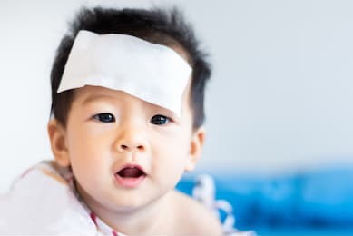 unhappy asian little baby child sick with cool fever jel pad on forehead