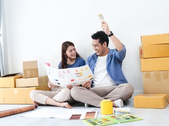 happy asian couple choosing colour palette for their new house, lifestyle concept.