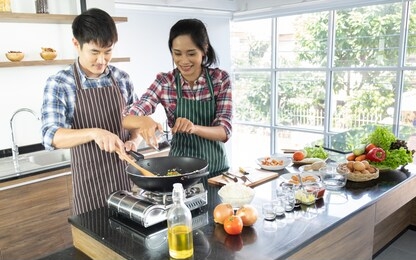 young asian couple are happy to cook together, two families are helping each other prepare to cook in the kitchen. with copy space