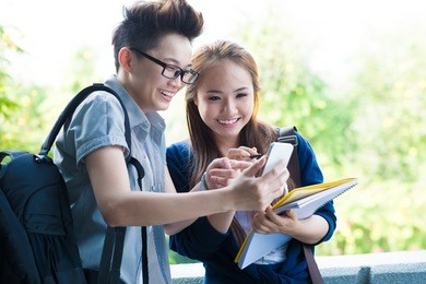 image of students standing and pointing at their phone