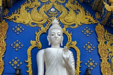 close up the white beautiful buddha statue in blue background and golden thai art decoration at wat rong suea ten,chiang rai province ,thailand.