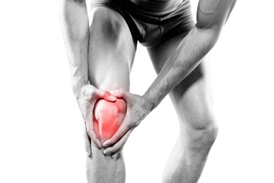 young sport man with strong athletic legs holding knee with his hands in pain after suffering ligament injury during a running workout training isolated on white background