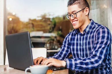 happy chinese young man using laptop computer 