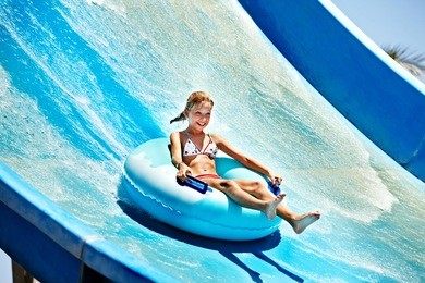 child on water slide at aquapark. summer holiday.