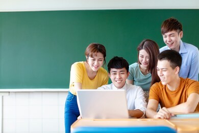 class of university students using laptops in classroom