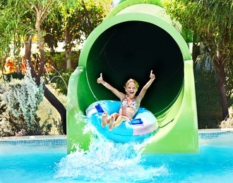 child on water slide at aquapark. summer holiday.