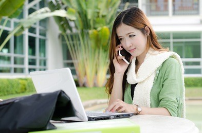 beautiful young student looking at computer notebook and on the phone