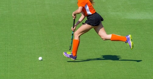 young hockey player woman with ball in attack playing field hockey game