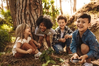 group of cute kids sitting together in forest and looking at camera. cute children playing in woods.
