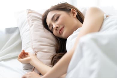 closeup portrait of a calm young pretty asian woman sleeping in her bed and relaxing in the morning. lady enjoying sweet dreams and enough rest concept