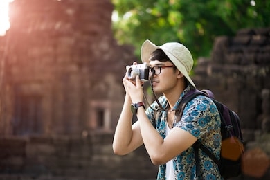 young man photographer traveler with backpack taking photo with his retro film camera, great wall in background at historical place. lifestyle and travel concept.