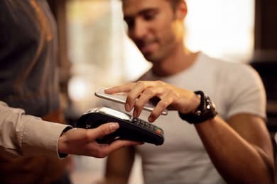 close up of guest using smart phone while making contactless payment in a pub. 