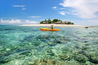 young woman kayaking near south sea island, mamanuca islands group, fiji. this group consists of about 20 islands.