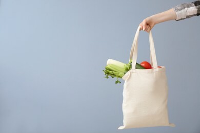 female hand with eco bag on grey background. zero waste concept