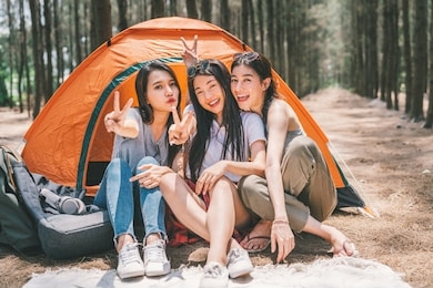 group of happy asian teenage girls doing victory pose together, camping by the tent. outdoor activity, adventure travel, or holiday vacation concept