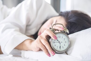 asian woman sleeping on bed hand turn off alarm clock waking up in the morning 
