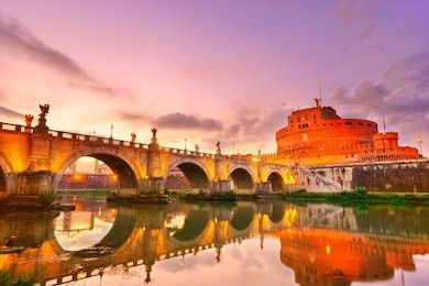 view of the castel sant'angelo and aelian bridge in rome at sunset.