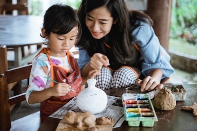 mother and daughter painting ceramic pot in pottery workshop