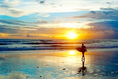 surfer on the ocean beach at sunset on bali island, indonesia
