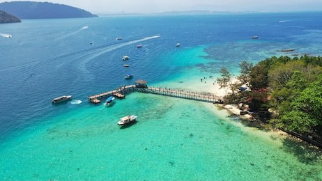 wooden jetty on manukan island beach with dinghy boat on sea.