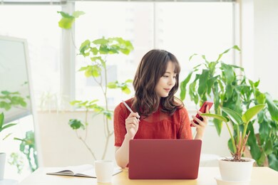 young asian woman using a smart phone and a laptop pc.