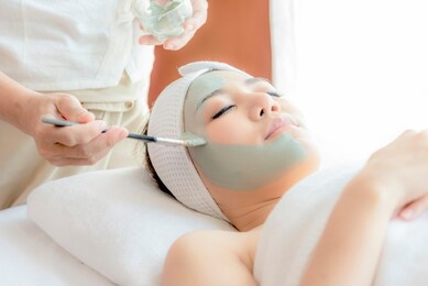 close-up side view relaxing beautiful young asian woman enjoy relaxing getting during face peeling mask skin care spa beauty treatment by beautician at spa salon center.