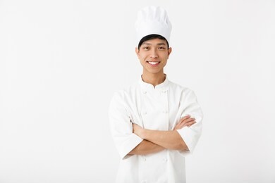 excited asian chef wearing uniform standing isolated over white background, gesturing