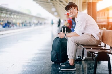 asian man is traveler, he is waiting for their train. outdoor adventure travel by train concept. bangkok, thailand. happy/positive/healthy hike/travel/wanderlust concept