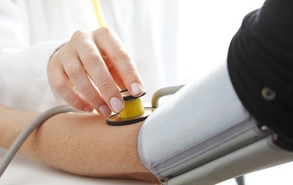close-up of doctor/nurse checking blood pressure with stethoscope