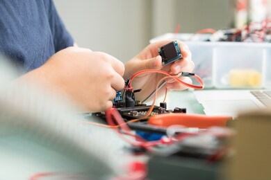 closeup of a child's hands working with circuits, wires, computer chip, oled, motor, wheels on his robotics project. science, technology, engineering and mathematics (stem) education concept.