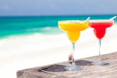 two perfect mango and strawberry margarita, beach background
