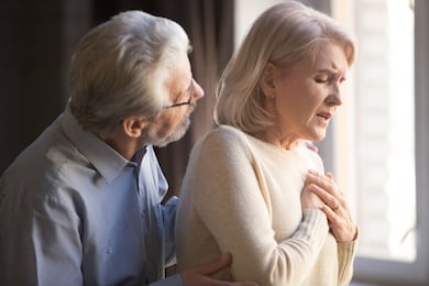 close up focus on elderly wife hold hand on breast touch chest having heart attack feels unwell, worried husband supporting her, myocardial infarction symptoms, immediately emergency call need concept