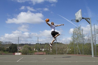 portrait of a basketball player in mid air about to slam dunk