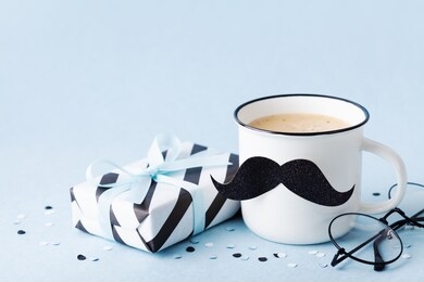 creative breakfast on happy fathers day with gift box and funny face from cup of coffee and moustache.