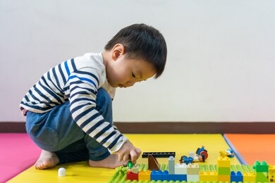 a boy playing with colorful plastic bricks at home. development step for a boy to learn and build a car. education concept- image