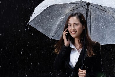 asian woman are using umbrellas, rain is falling.she is talking on the phone