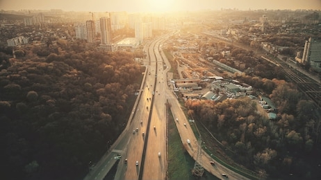 urban car road traffic congestion aerial view. city street motion lane, drive navigation overview. busy cityscape speed route with forest park around. travel concept drone flight shot