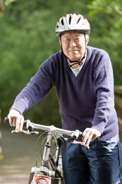 a shot of a mature asian man riding a bike