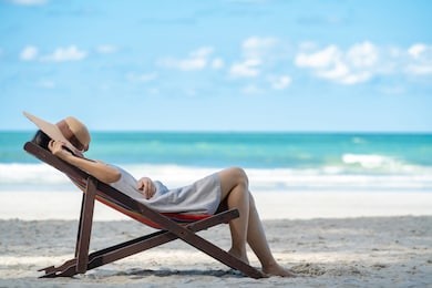 young adult asian woman tourist in casual wear sleeping nap on beach sun bed on tropical island sand beach in summer day holidays vacation travel trip with blurred blue sea, beach and sky backgrounds.