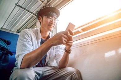 asian man is traveler, he is waiting for their train. outdoor adventure travel by train concept. bangkok, thailand. happy/positive/healthy hike/travel/wanderlust concept