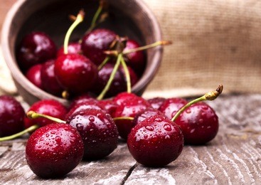 cherries on wooden table with water drops macro background