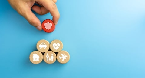 insurance concept. wooden blocks with insurance icons. family, life, car, travel, health and house insurance icons. blue background with copy space